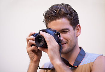 Image showing Man, camera and photographer in studio for shooting, digital lens and tech for image or picture. Male person, hobby and equipment for photo on white background, production and capture for memories