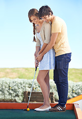 Image showing Young couple, love and outdoor for mini golf in nature, bonding together and happy on weekend with hobby. Man, woman and putt on romantic trip and care, sunshine and teaching girlfriend to play game