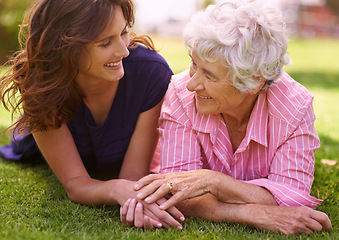 Image showing Senior, mother and happy outdoor with woman to relax on grass in summer, holiday or vacation together. Elderly, mom and family holding hands with love and support and smile in retirement in garden