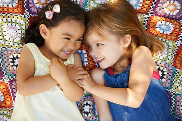 Image showing Happy, nature and girl kids on blanket playing together in outdoor park or garden on vacation. Smile, bonding and high angle of young children friends relaxing in field on holiday or weekend.