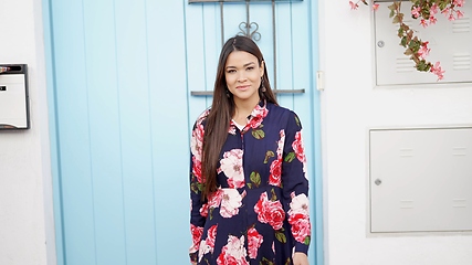 Image showing Confident Woman in Floral Dress Standing by Blue Door