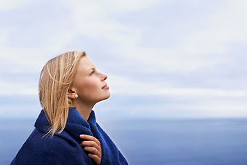 Image showing Thinking, ocean and woman with blanket with blue sky for adventure on holiday, vacation and weekend outdoors. Nature, travel and person by seaside for relaxing, happiness and peace in countryside