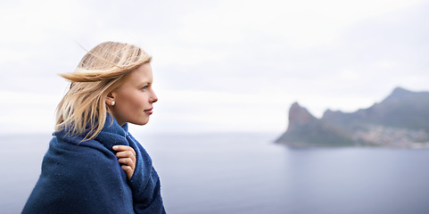 Image showing Thinking, ocean and woman with blanket in nature for adventure on holiday, vacation and weekend outdoors. Mountain, travel and person by seaside for relaxing, happiness and peace in countryside