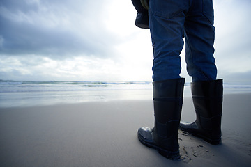 Image showing Travel, boots and shoes of person at beach for ocean, tourism and walking in sand. Adventure, vacation and calm with feet of traveler and gumboots at seaside for relax, holiday trip and journey