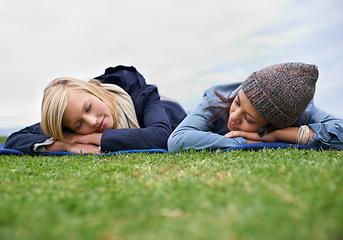 Image showing Sleeping, grass and women relax in field with smile, happy and resting on weekend outdoors. Friends, countryside and people lying in meadow for bonding on holiday, vacation and adventure in nature