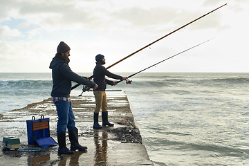 Image showing Fishing, friends and travel with men at beach for adventure, holiday and hobby break. Sunset, calm and patience with male fisherman and casting rod pole in nature for recreation, view and vacation