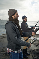 Image showing People, sea and friends with fishing pole at beach, relaxing and casting a line by ocean. Men, fisherman and cloudy sky on vacation or holiday, hobby and bonding by waves and support on adventure