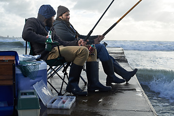 Image showing Ocean, pole for fishing and men outdoor in winter, leisure activity at beach or harbor with friends in nature for seafood. Travel, seascape and waves with fisherman, recreation or hobby in the cold