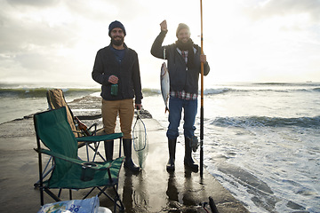 Image showing Happy, portrait and men fishing at ocean with pride for tuna catch on pier at sunset. Fisherman, friends and smile holding fish and rod in hand on holiday, adventure or vacation in nature at sea