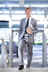 Image showing Business man, newspaper and travel at airport for portrait with walking, suitcase and commute on trip. Professional person, luggage and corporate employee with pride on steps with suit in lobby