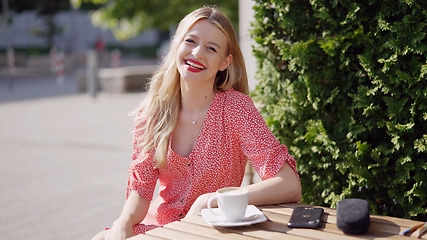 Image showing Smiling Woman Enjoying Coffee Outdoors on a Sunny Day