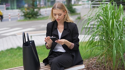 Image showing Professional Woman Checking Phone on City Bench