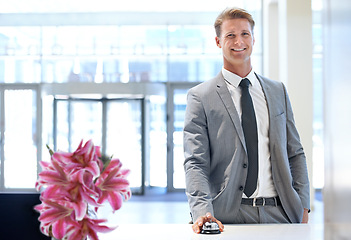 Image showing Happy businessman, portrait and bell at reception desk for hotel reservation, stay or check in. Man or employee with smile in stylish business suit at counter for assistance, help or service at lodge