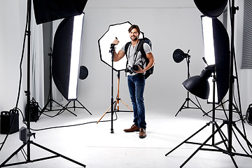 Image showing Photographer, portrait and lighting with equipment in studio for career, behind the scenes or electronics. Photography, person or happy with cameras, flash and shooting gear for photoshoot or passion