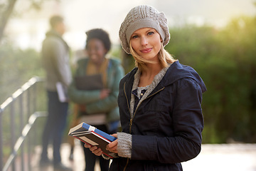Image showing Closeup, winter and university student with book in outdoor on campus, happy and smile with support and care. Education, college with notes to prepare for exam, assessment and texbook to study.
