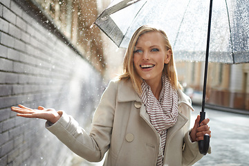 Image showing Woman, umbrella and hand with rain in city, walking and surprise for splash, weather and happy in winter. Person, wow and smile with travel, journey and excited with water on sidewalk in Cape Town