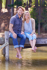 Image showing Mature couple, lake and sitting on dock, countryside and commitment with love in marriage. Happiness, smile and hug by partner, family and woman with man vacation for sightseeing in nature to relax
