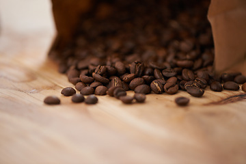 Image showing Table, closeup and fresh roasted coffee beans, spilling from a paper bag onto a vintage wood counter with copy space. Studio, aromatic bitter caffeine to feel refreshed with hot, refreshing beverage