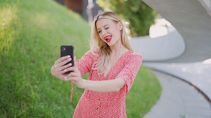 Image showing Young Woman in Red Dress Using Smartphone Outdoors