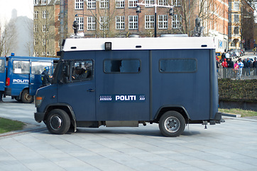 Image showing Police, van and city for transport, safety or protection service for public justice in in street. Vehicle, law enforcement and outdoor for danger, arrest and armored truck on urban road in Copenhagen