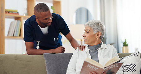 Image showing Senior, woman and nurse on sofa with support, conversation and caregiver in living room of retirement home. Elderly, person and black man with kindness, happiness and discussion while reading a book