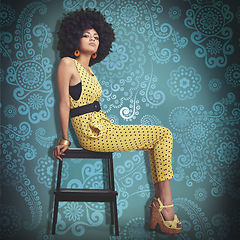 Image showing Portrait, young woman and fashion in 70s retro colour jumpsuit and sitting on chair. African trend, elegant model pretty in vintage outfit, big curly hair and wedge heels on cool pattern background