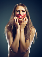 Image showing Portrait, rage and woman with anger, blood and person on a dark studio background. Face, model and girl with expression or upset with emotion and furious with stress and emoji with conflict or crisis