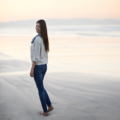 Image showing Woman, walking and happy in portrait by ocean, sunset and vacation with nature to relax at beach. Girl, person and outdoor by sea with feet in sand for holiday, adventure or smile by sea in Australia