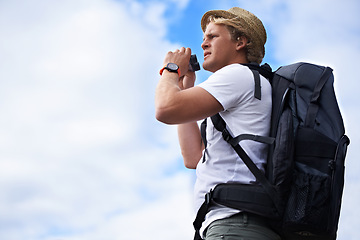 Image showing Man, tourist and binoculars with backpack for hiking, sightseeing or outdoor travel with blue sky background. Male person or young traveler with bag or optical instrument for view, vision or scope