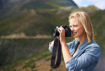 Image showing Happy woman, blonde and camera for outdoor photography, picture or sightseeing on mountain. Young female person or journalist with smile for photo, view or memory in natural environment in nature