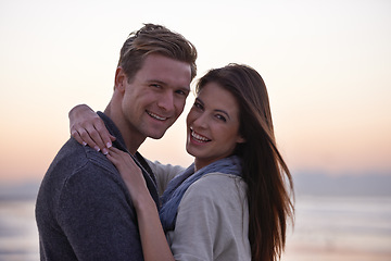 Image showing Sunset, hug and portrait of happy couple on beach for tropical holiday adventure, love and bonding together. Evening, happy man and woman on romantic date with ocean, sky and embrace on vacation.