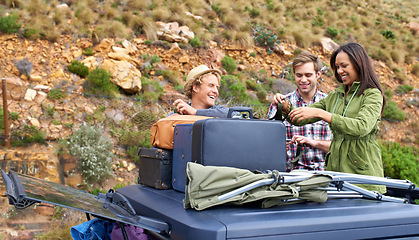 Image showing Friends, group and luggage on car roof for road trip together or camping holiday as explore, mountain or vacation. Men, woman and unloading bags on vehicle in Italy or travel, journey or suitcase