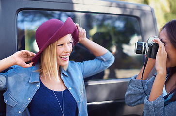 Image showing Camera, photography and friends on road trip with journey, travel and creative hobby or photoshoot of model posing. Young people, women or photographer shooting by car for outdoor fashion and hat