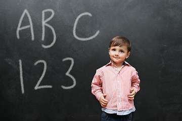 Image showing Child, boy and face with smile by blackboard with letters, numbers and happiness in classroom at school. Kid, student and happy for knowledge, learning and chalkboard with math, alphabet or preschool