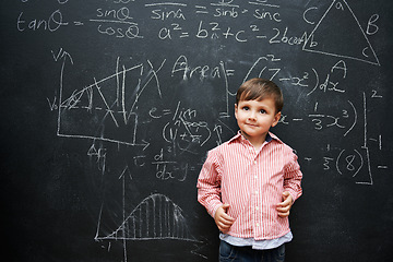 Image showing Kid, boy and face with smile by blackboard with equations, numbers and problem solving in classroom at school. Child, student and happy for knowledge, learning and chalkboard with math and preschool