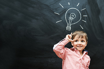 Image showing Child, thinking and lightbulb on chalkboard for solution, learning and creative mindset in school on mockup space. Happy kid, student or boy with light bulb, emoji and blackboard of knowledge or idea