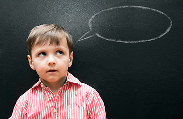 Image showing Child, boy and thinking with speech bubble on blackboard for creative idea, drawing and illustration in classroom. Student, kid and face with daydreaming, contemplating and question with chalkboard