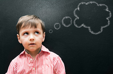 Image showing Child, boy and thinking with thought bubble on blackboard for creative idea, drawing and illustration in classroom. Student, kid and face with daydreaming, contemplating and question with chalkboard