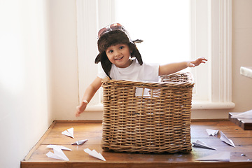 Image showing Flying, fun and child with paper plane, fantasy, and imagination playing in basket in home. Adventure, little pilot and playful boy in box with future dream, growth and development with airplane.