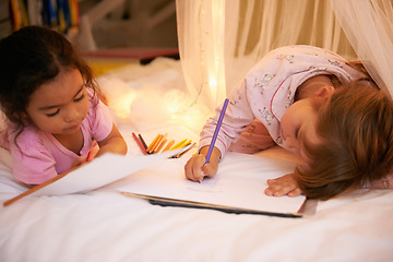 Image showing Kids, color pencil and drawing on bed for sleepover, creative and relax in bedroom for weekend. Young girls, playing and learning art in book at night, friends and bonding by fairy light in pyjamas