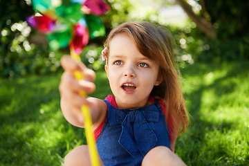 Image showing Toy, girl and child playing with windmill on grass in nature, relax and having fun on lawn outdoor. Park, garden and young kid with pinwheel on summer vacation closeup for recreation, game or leisure