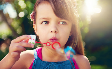 Image showing Park, girl and child blowing bubbles in nature, relax and having fun outdoor. Toy, garden and face of kid with soap on summer vacation for recreation, leisure and playing game closeup for freedom