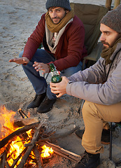 Image showing Men, sunset and campfire with portrait, smile and beer with travel adventure and journey outdoor. Friends, ocean and sea with bonding, winter and vacation by the beach together on holiday with fire