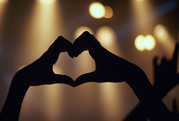 Image showing Person, hands and music concert with heart shape enjoying and loving the performance. Close up a finger sign during a live showing the music band on stage with support while partying with silhouette