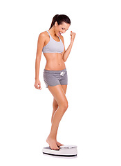 Image showing Fitness, celebration and woman on scale in studio for weight loss, health or wellness victory. Happy, sport and slim person on measuring body for exercise, workout or training by white background.