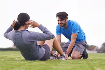 Image showing Personal trainer, man and woman with sit ups on grass for fitness, training and helping hand in summer. People, support and motivation for abdomen exercise with workout on park lawn in Australia