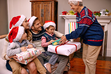 Image showing Christmas, big family and giving gift in living room with smile, gratitude and bonding together in home. Grandmother, parents and children with present, love and festive holiday celebration on sofa.