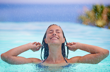 Image showing Face, smile and rain with woman in swimming pool for travel, holiday or vacation as tourist. Relax, water and wellness with happy young swimmer person outdoor at tropical resort for getaway trip