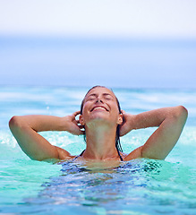 Image showing Smile, swimming pool and water with woman on holiday or vacation in summer to relax for travel. Trip, wellness and tropical with happy young person on blue sky for getaway, joy or fun outdoor