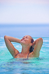 Image showing Face, smile and raining with woman in swimming pool for travel, holiday or vacation as tourist. Relax, water and wet with happy young swimmer person outdoor at tropical resort for hospitality